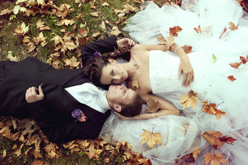 Wedding theme bride and groom are in maple leaves on grass