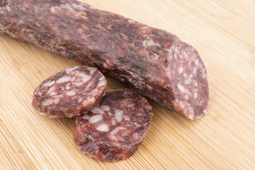 Dried sausage and slices on wooden board