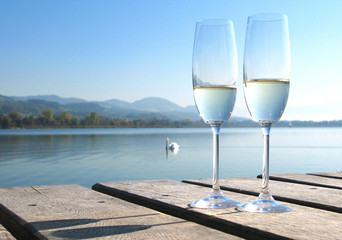 Two champagne glasses against a lake