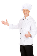 Mature chef holding empty space in hands