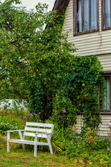 Country house, garden and a wooden bench in front of house