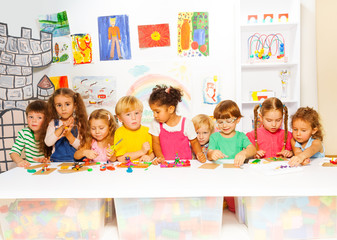 Large group of kids play with plasticine in class