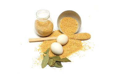 Millet in the bank, a wooden spoon, eggs and bay leaf. Photo.