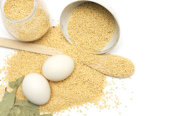 Millet in the bank, a wooden spoon, eggs and bay leaf. Photo.