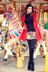 Fashion model posing on carousel in red coat