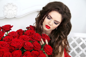 Beauty model girl with makeup, long hair and beautiful red roses