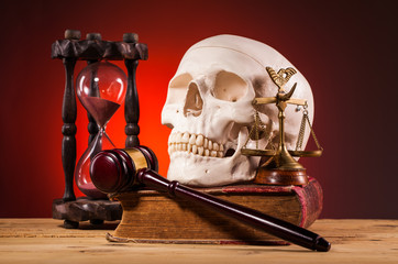 human scull, gavel, scales of justice and old book