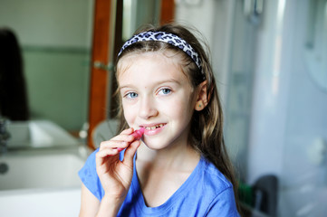 Little girl with lipstick and mirror. Makeup