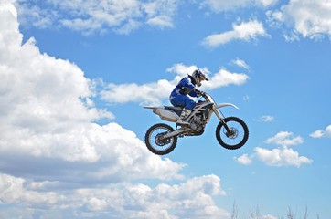 Fototapeta na wymiar Motocross driver standing on the MX bike is flying over the