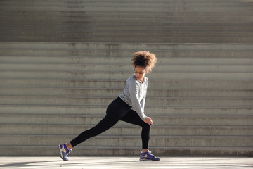 Side view portrait of a young woman stretching leg muscles