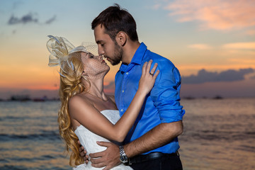 bride and groom on a tropical beach with the sunset in the backg