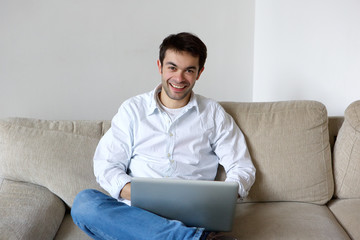 Smiling young man using laptop at home