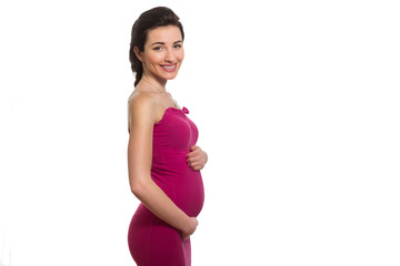 Young caucasian smiling pregnant lady in pink dress touching bel