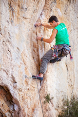 Young male rock climber on face of cliff