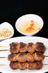 Vietnamese grilled pork meatballs, nem nuong, on black backgroun
