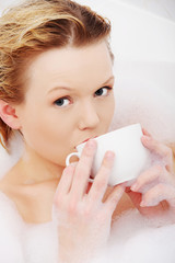 Woman relaxing in bath, drinking cup of coffee