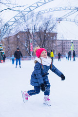 Adorable little girl skating on the ice-rink