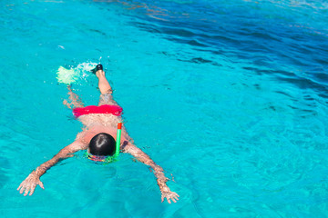 Young man snorkeling in clear tropical turquoise waters