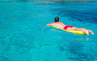 Young man relaxing on inflatable mattress in the sea
