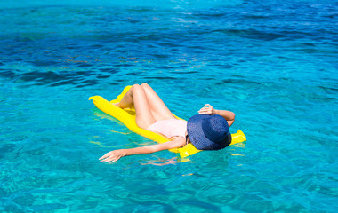 Woman relaxing on inflatable mattress in clear sea