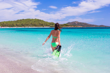 Young woman running into tropical blue sea with snorkeling gear