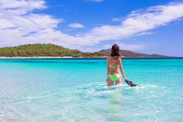 Young woman running into tropical blue sea with snorkeling gear