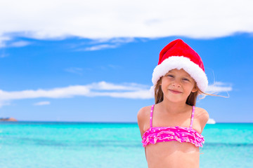 Little adorable girl in red Santa hat at tropical beach