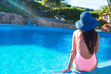 Beautiful young girl relaxing near the swimming pool