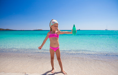 Naklejka na ściany i meble Little adorable girl in swimsuit with suntan lotion bottle
