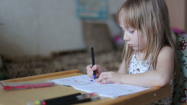 Little girl drawing with colored markers in the children's album