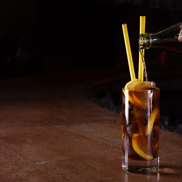 Barman prepares Cuba libre cocktail in a tall glass