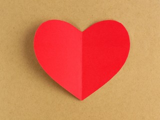 Red Valentines Day heart against a brown paper background