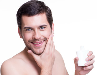 Young happy man applying cream.