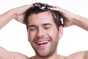Young happy smiling man washing hair.