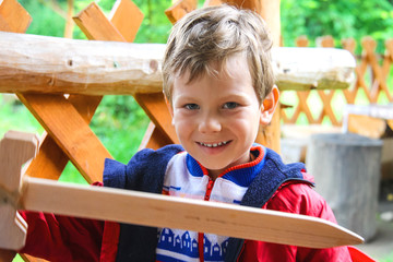 Smiling boy with a wooden sword at the playground
