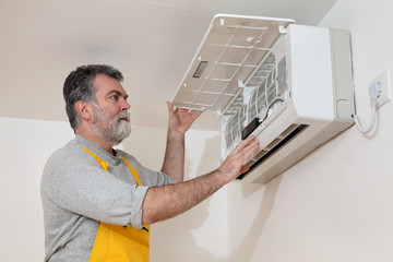 Electrician worker examine or install air condition in room