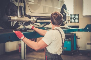 Young serviceman checking wheel alignment  in a car workshop