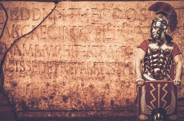 Roman legionary soldier in front of  wall with ancient writing