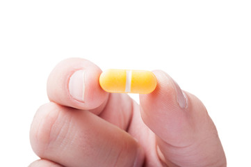 Closeup with a yellow pill hold between fingers