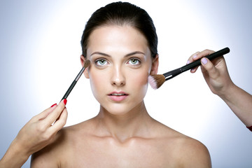 woman applying makeup on the face with brush