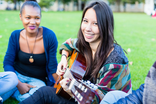 Gitarristin macht Musik mit Freuden im Park