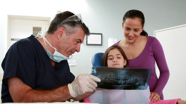 Dentist showing x-ray to little girl and her mother