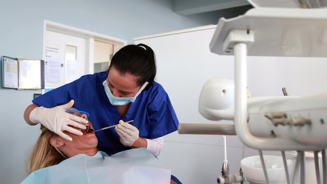 Pediatric dentist examining a patients teeth with angled mirror