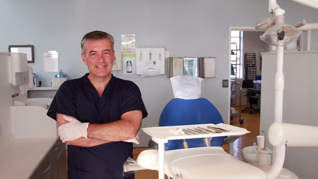 Smiling dentist standing with arms crossed