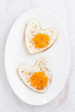 Fried eggs in the form of heart, top view, vertical