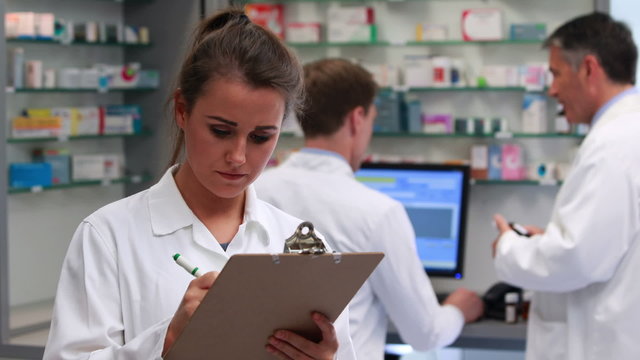 Junior pharmacist writing on clipboard