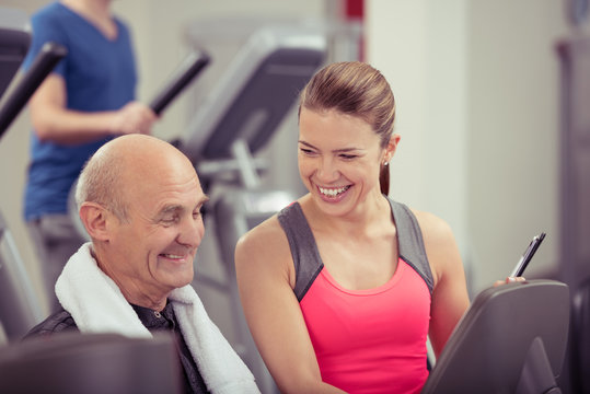 lächelnde trainerin im fitness-club berät senior