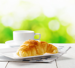 Cup of coffee and croissant on nature background