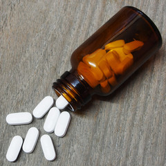 Pills spilling out of a pill bottle on wooden table