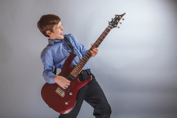 Teen boy playing guitar on gray background